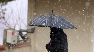 Ανθρωπος που κρατάει ομπρέλα ενώ χιονίζει 