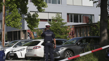 A police officer makes a phone call in front of a school building after a shooting Graz, Austria, Tuesday, June 10, 2025. 