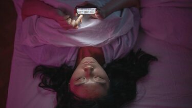 κινητό στο χέρι στο κρεβάτι